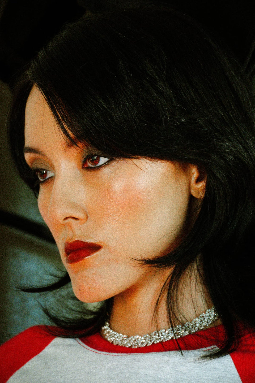 Close-up editorial portrait with vintage diamond choker and red lipstick in warm retro-styled lighting