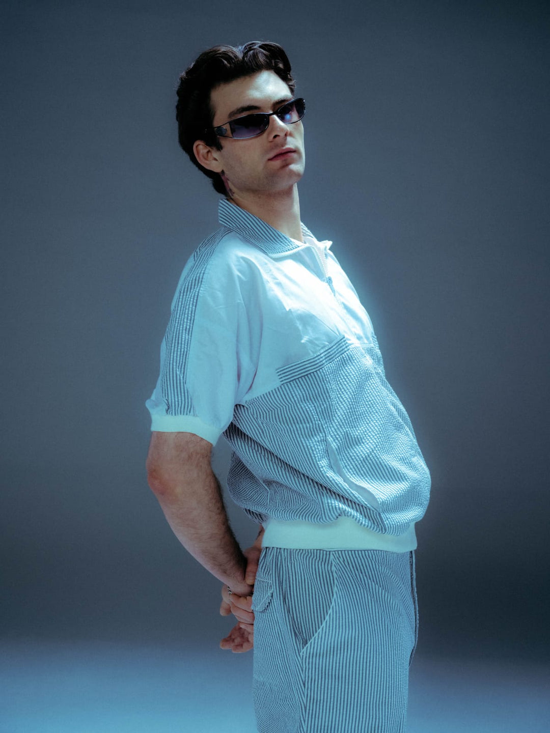 Model in vintage seersucker set with sunglasses photographed in cool blue studio lighting
