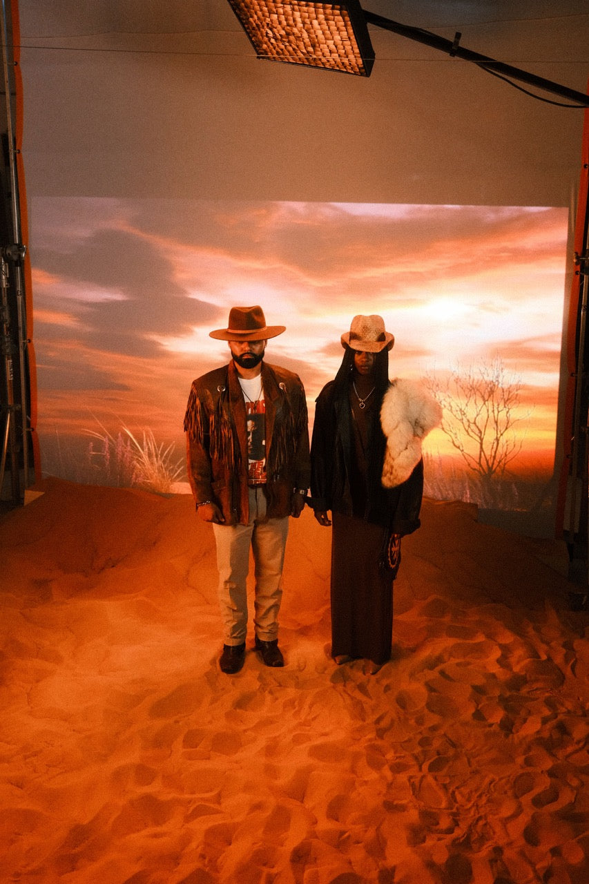 Two people in western wear on a red desert set