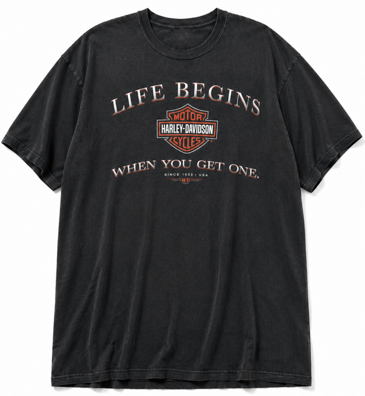 A faded black short-sleeve t-shirt featuring a distressed Harley-Davidson logo and the text 'LIFE BEGINS WHEN YOU GET ONE.' printed on the front, displayed against a solid white background.