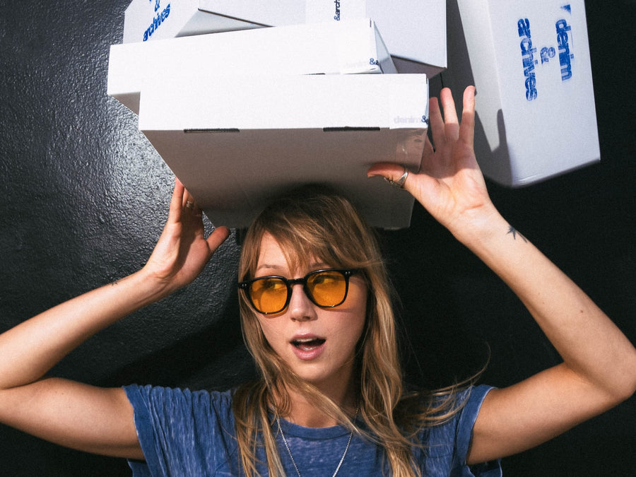 Stack of Denim & Archives shipping boxes balanced on a model's head