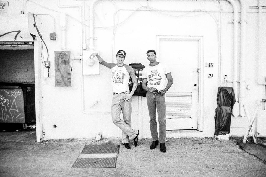Black and white: two friends in vintage ringer tees against a white alley wall