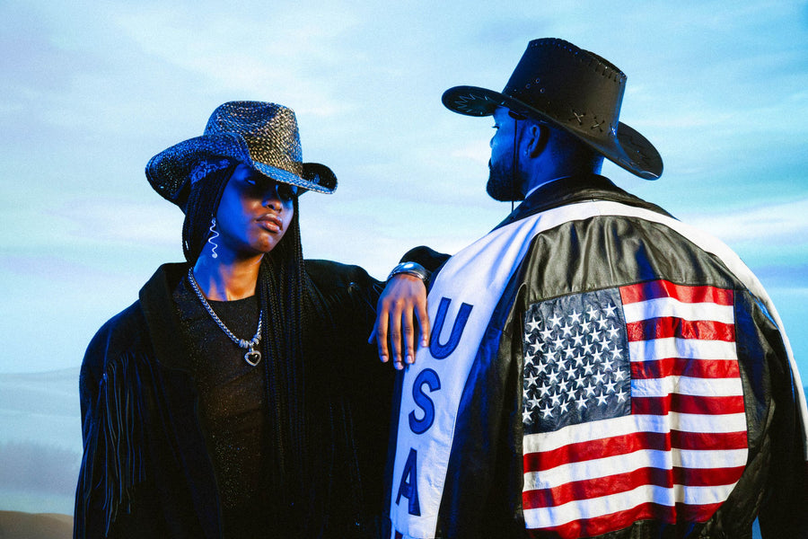 Two friends in cowboy hats, one in a leather USA flag jacket