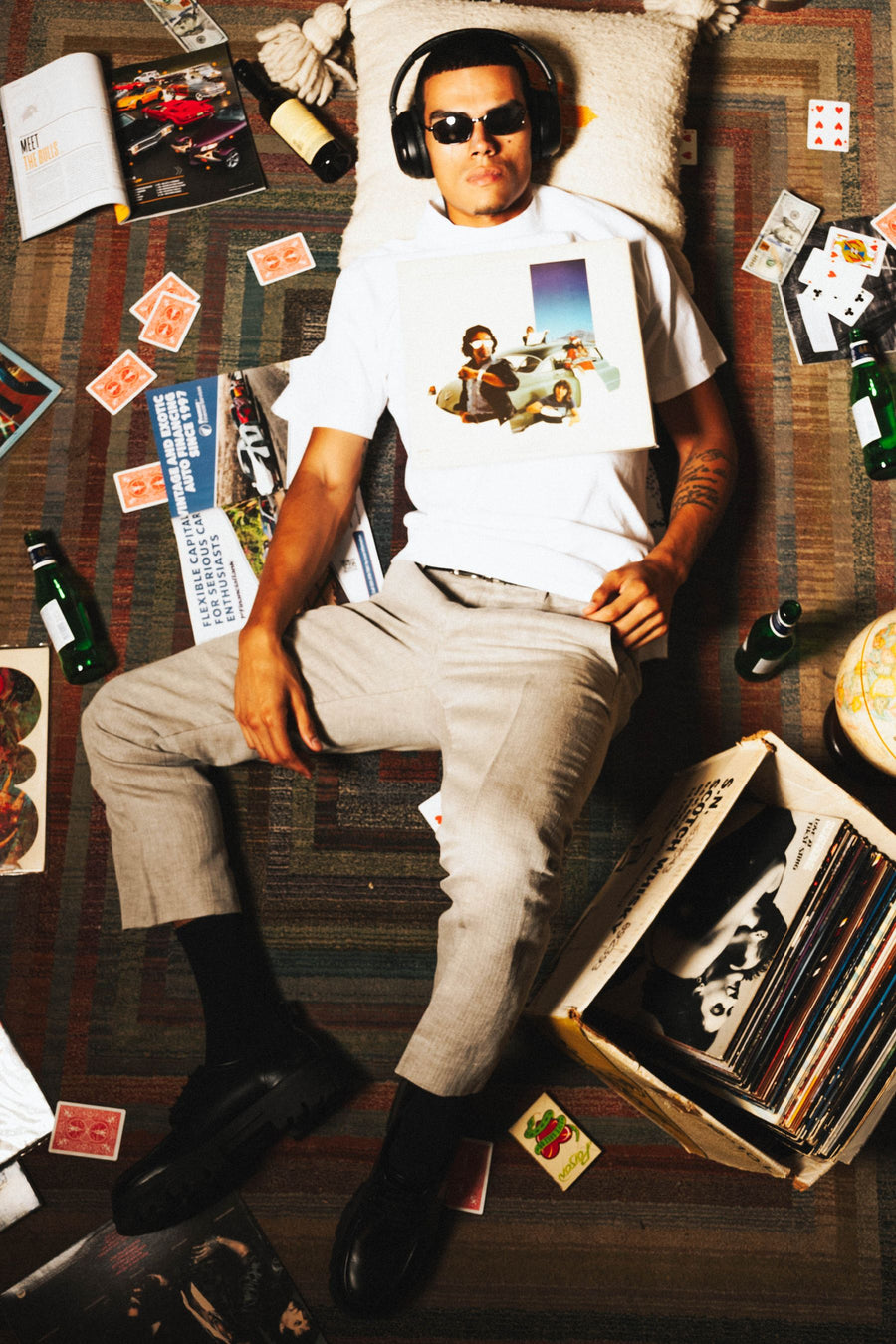 Lying on a rug among records, magazines and playing cards