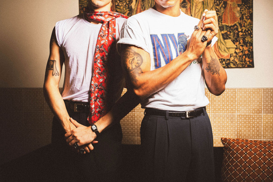 Two friends in white tees, belts, rings and a red floral scarf